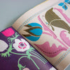 An open book or magazine showing two illustrated floral pages with bold pastel and bright patterns, photographed on a light blue-grey surface.