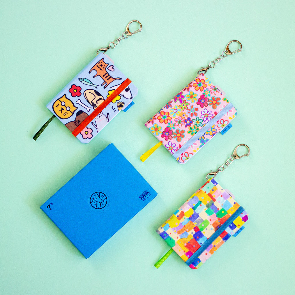 Set of colourful notebooks with keychains on a light green background