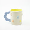 Ceramic mug with floral decorations and blue handle on a white background