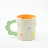 Ceramic mug with floral designs and mint green handle on a white background
