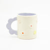 Closeup photo of the Lilac 3D flower mug. Mug has light glaze with lilac interior glaze. Flower shaped handle is lilac coloured. Mug has raised 3D style flowers that are hand painted and glazed in different colours. 