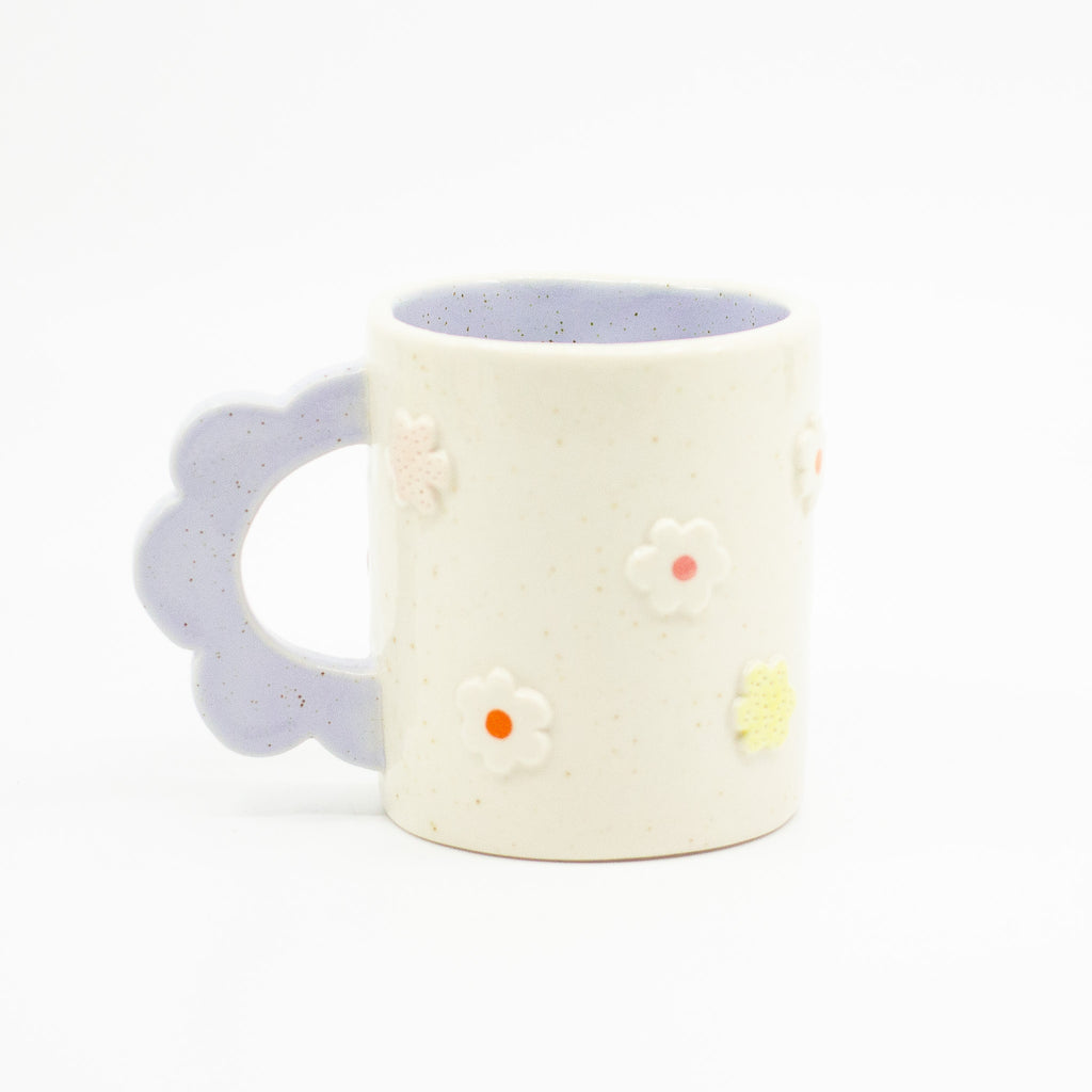 Closeup photo of the Lilac 3D flower mug. Mug has light glaze with lilac interior glaze. Flower shaped handle is lilac coloured. Mug has raised 3D style flowers that are hand painted and glazed in different colours. 