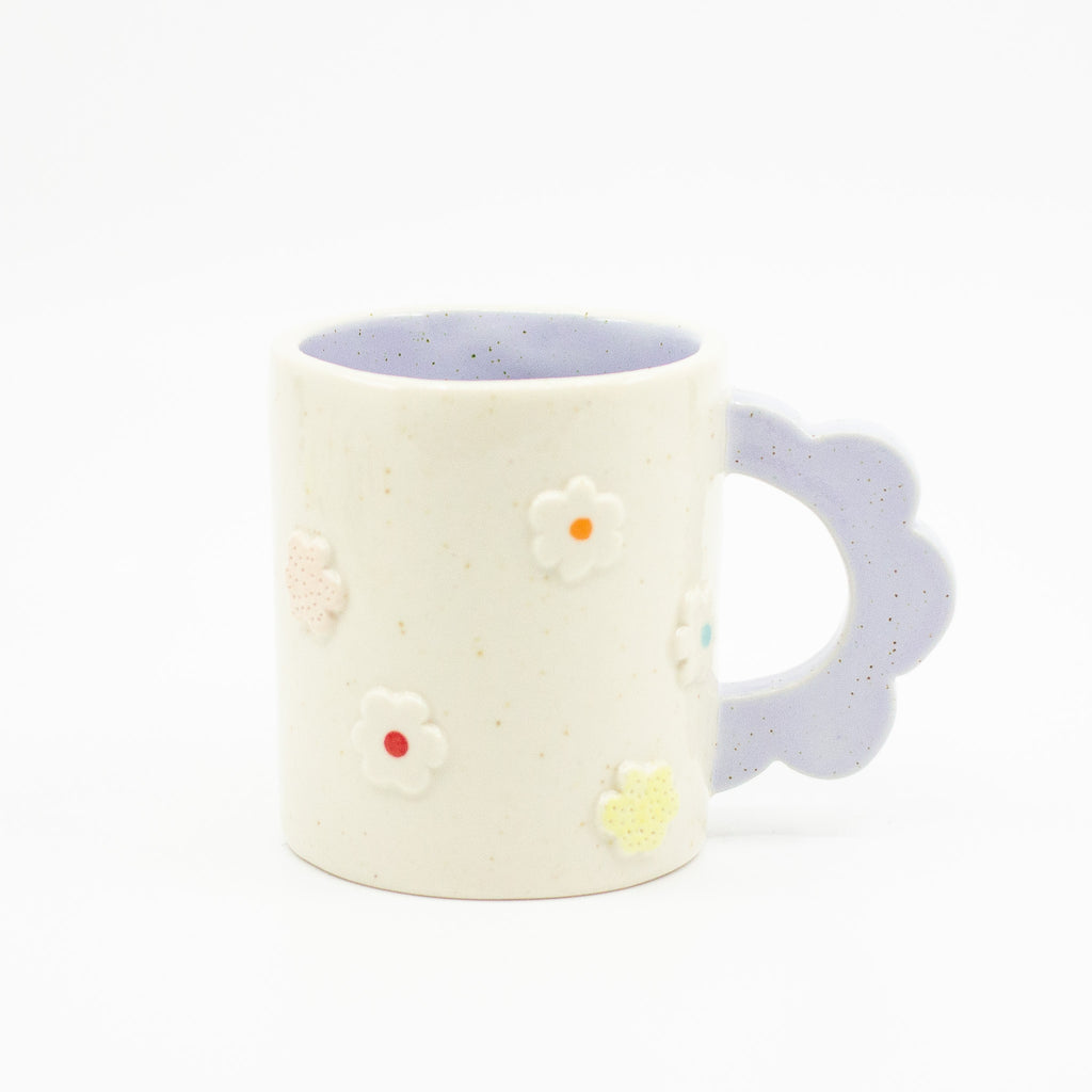 Closeup photo of the Lilac 3D flower mug. Mug has light glaze with lilac interior glaze. Flower shaped handle is lilac coloured. Mug has raised 3D style flowers that are hand painted and glazed in different colours. 