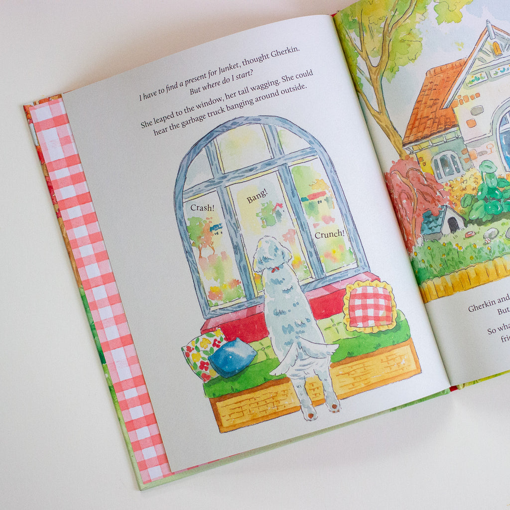 Open book with colourful illustrations of a dog by a window and a house outside.