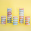 Stacked pastel-coloured cylindrical ceramic figurines on a yellow background