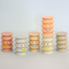 Set of colorful stacked ceramic figurines with smiley face designs on a light gray background