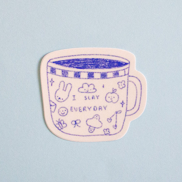 A die-cut sticker featuring a cute blue line art illustration of a mug with the text 'I SLAY EVERYDAY' and small doodles, shown on a light blue background.