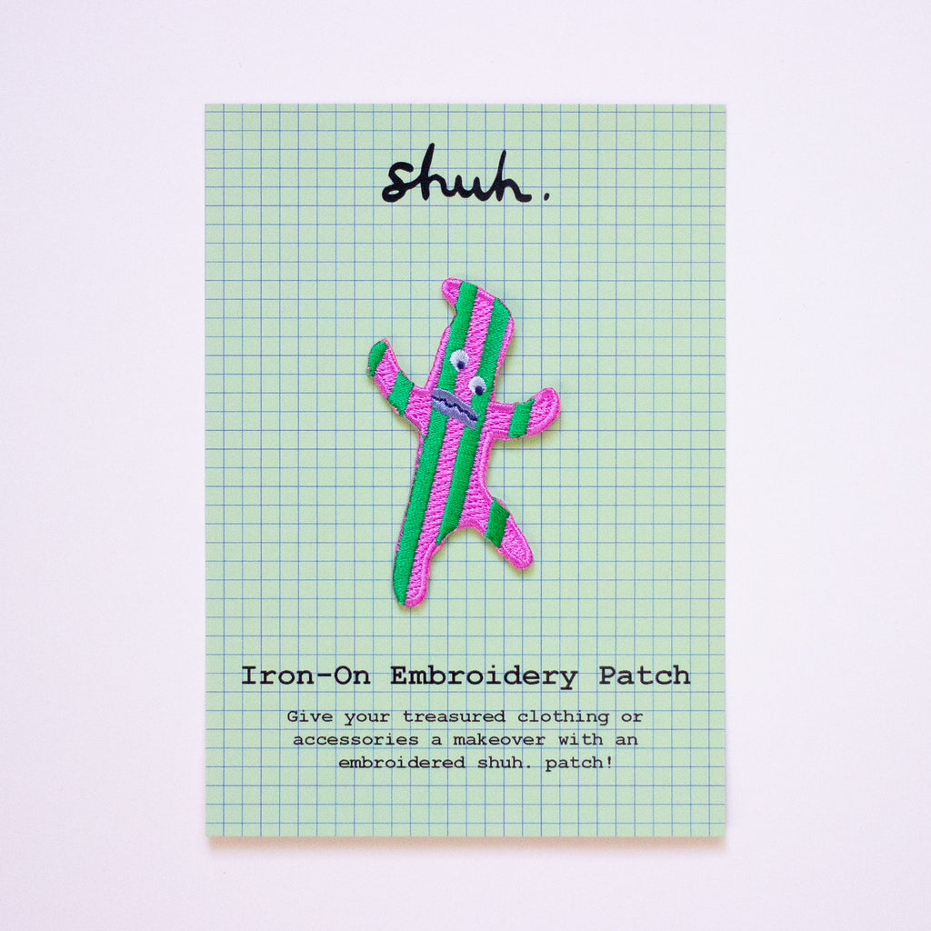 Iron-on embroidery patch with a stripey design and on a green grid background.