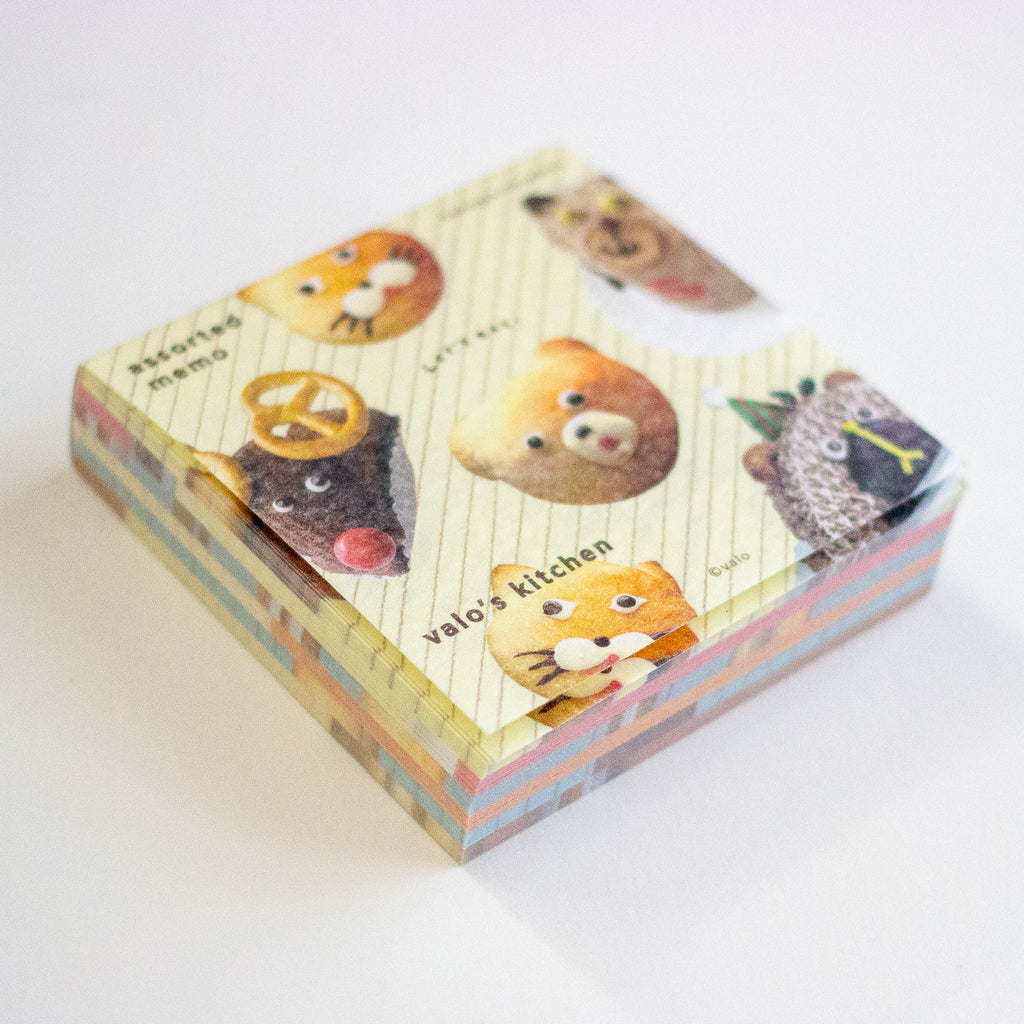 A stack of cute illustrated memo sheets with animal character designs and pastel striped edges, photographed on a clean white background.