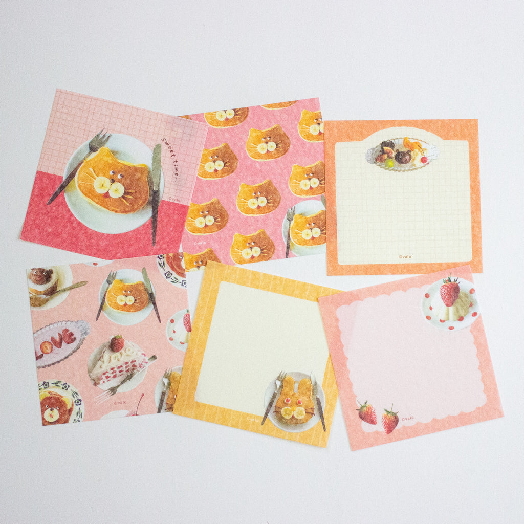 A set of cute breakfast-themed stationery memo sheets with illustrations of pancakes, strawberries, and cat faces on pink, orange, and yellow backgrounds.