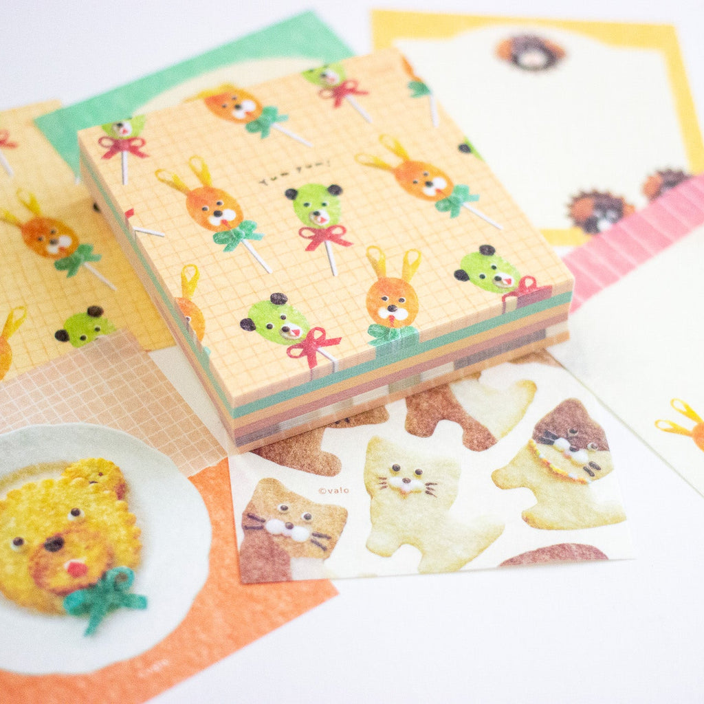A collection of cute, pastel-coloured stationery items featuring cartoon animal illustrations, including a stack of patterned memo sheets of animal-shaped food, arranged on a white background.
