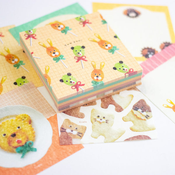 A collection of cute, pastel-coloured stationery items featuring cartoon animal illustrations, including a stack of patterned memo sheets of animal-shaped food, arranged on a white background.