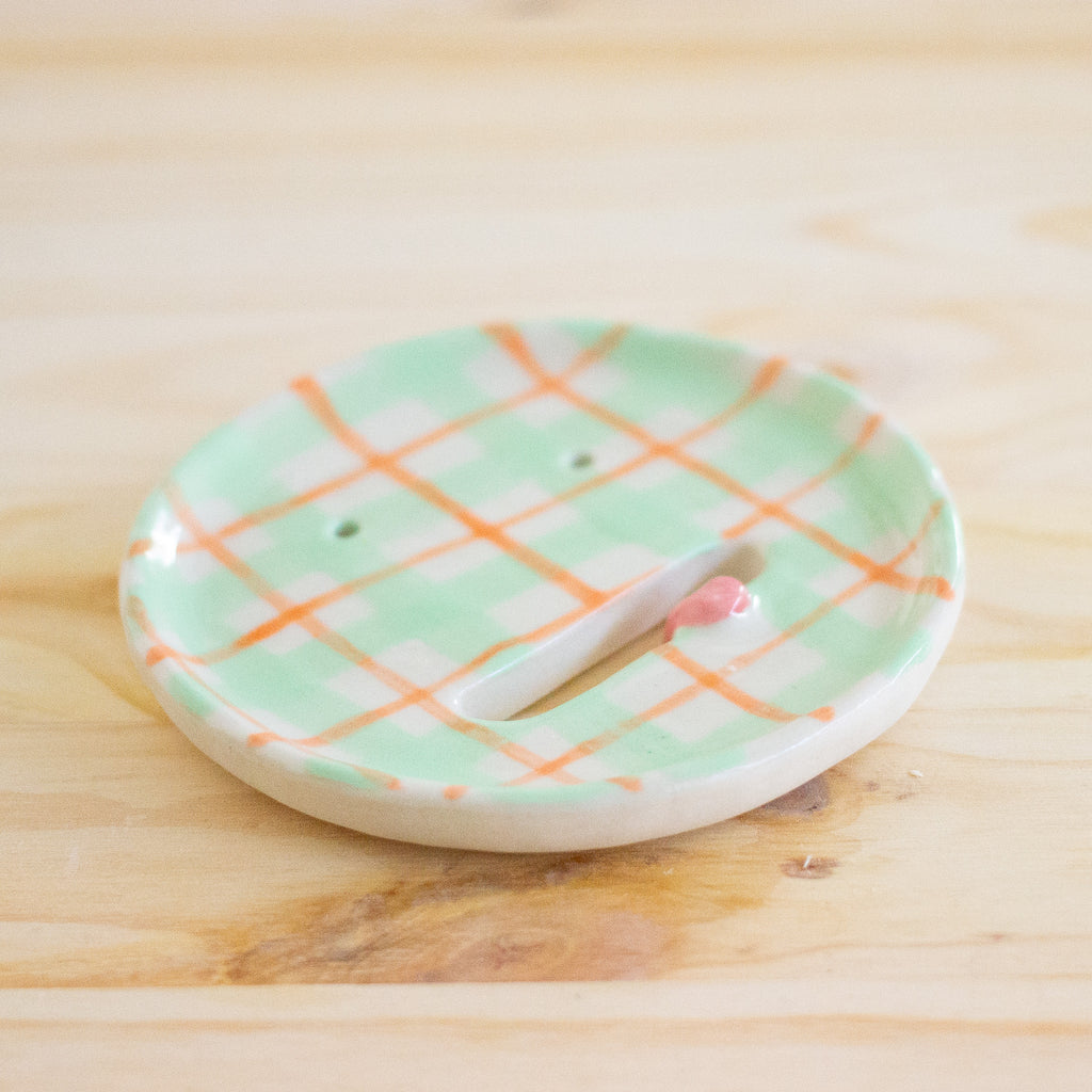Side view of the aster ceramic pottery soap dish. Green, orange and white tartan paint. Pink tongue and mouth opening. 