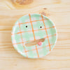 Top view of the aster ceramic pottery soap dish. Green, orange and white tartan paint. Pink tongue and mouth opening. 