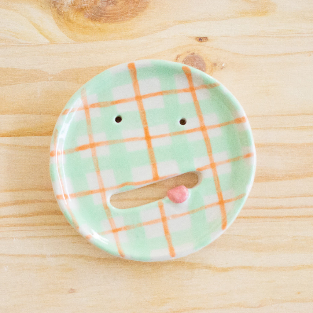 Top view of the aster ceramic pottery soap dish. Green, orange and white tartan paint. Pink tongue and mouth opening. 