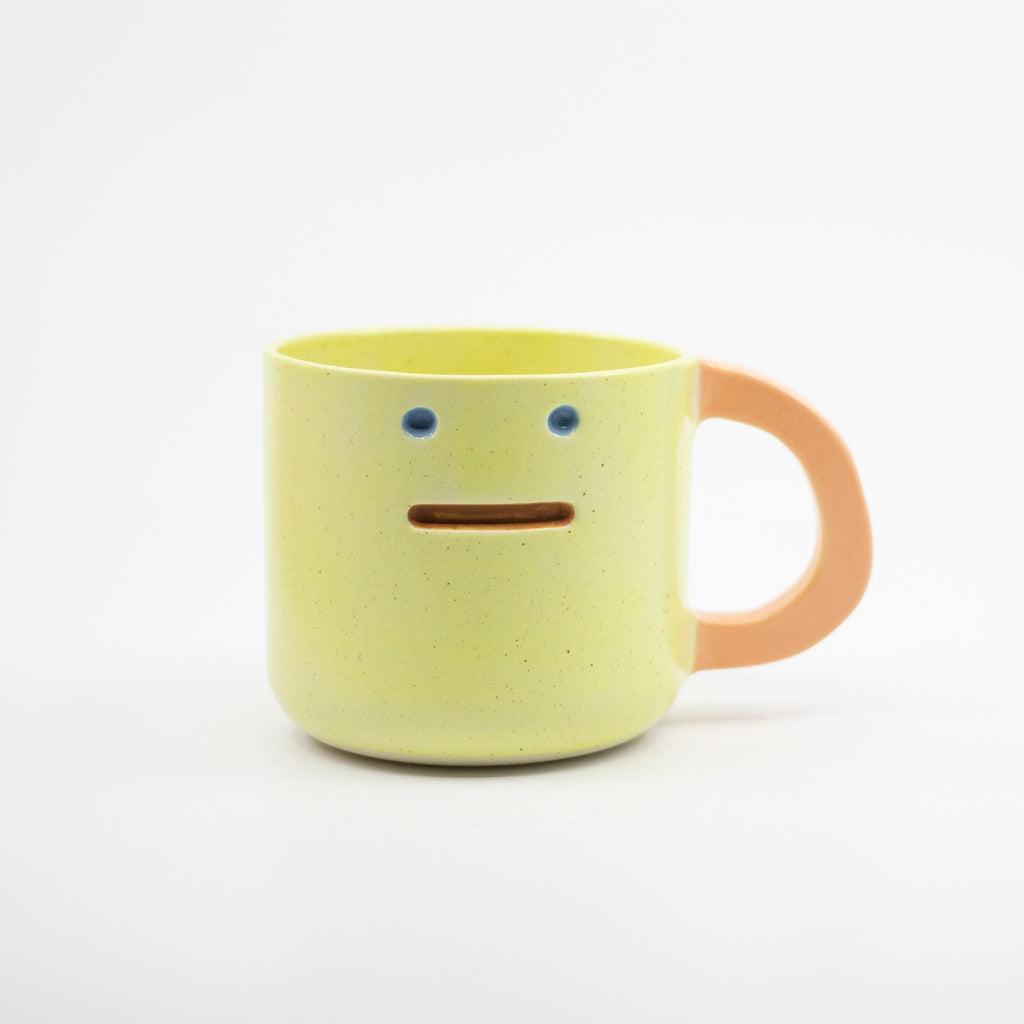 Yellow mug with a smiley face on a white background