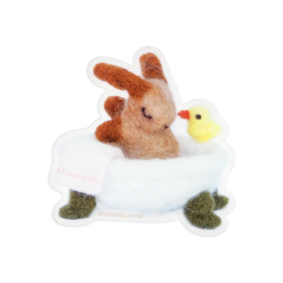 Sticker of a small plush toy of a rabbit sitting in a bath tub with a duckling on a white background