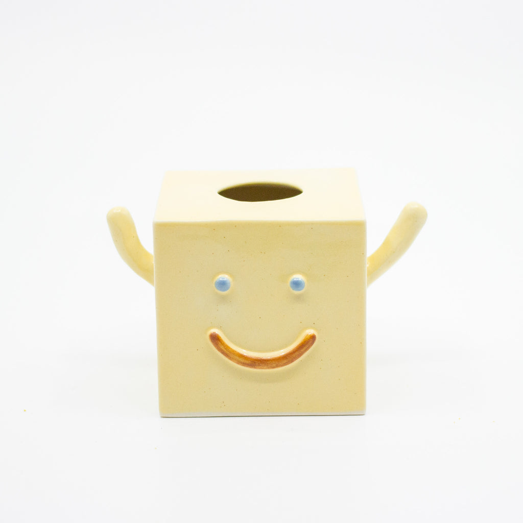 Yellow cube-shaped vase with a smiley face on a white background