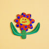 Colorful embroidered flower patch with a face on a yellow background