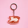 A keychain with an illustration of a lamb lying down with the words 'TOO CUTE TO DO MATHS' with a clear outline against a pink background. 