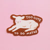 An illustrated sticker of a lamb lying down with the words 'TOO CUTE TO DO MATHS' with a brown outline against a pink background. 