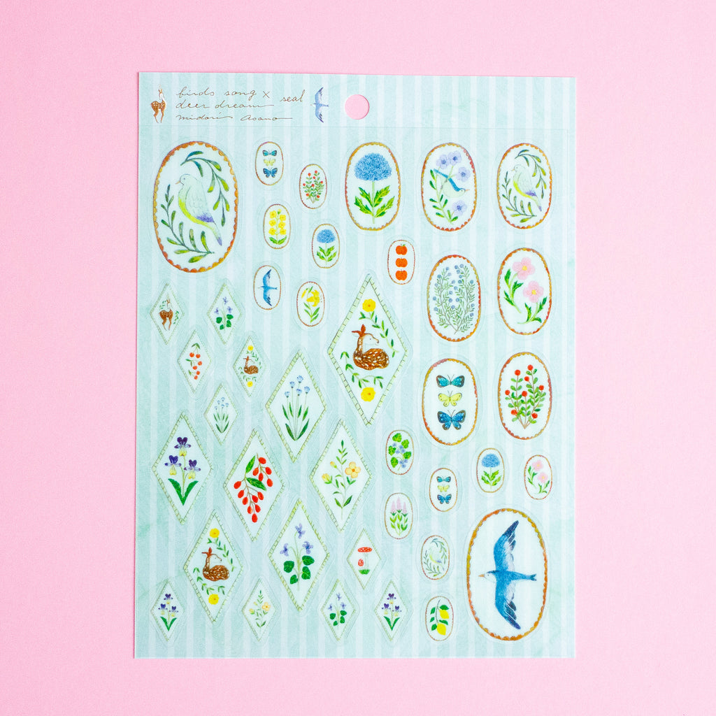 A sheet of decorative stickers featuring various floral, bird, and nature motifs on a pale blue striped background, displayed against a solid pink backdrop.