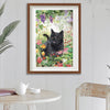 Framed artwork of a black cat among flowers on a wall above a table.
