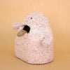 Side view of the Handbuilt ceramic figurine by shuh. with a speckled pink glaze, open mouth, and protruding tongue. Sculptural artwork made from stoneware clay for the Well Wishes exhibition.