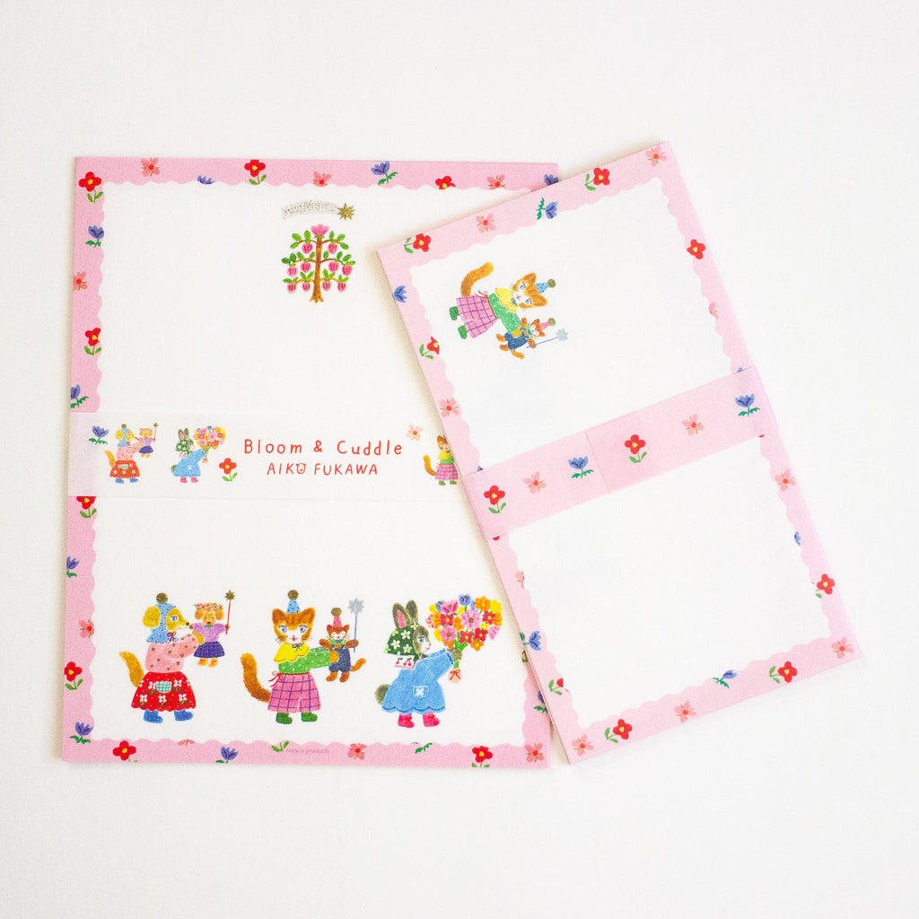 A letterset pink and white stationery sheets and envelopes with colourful cartoon animal illustrations and floral borders, arranged on a plain white background.