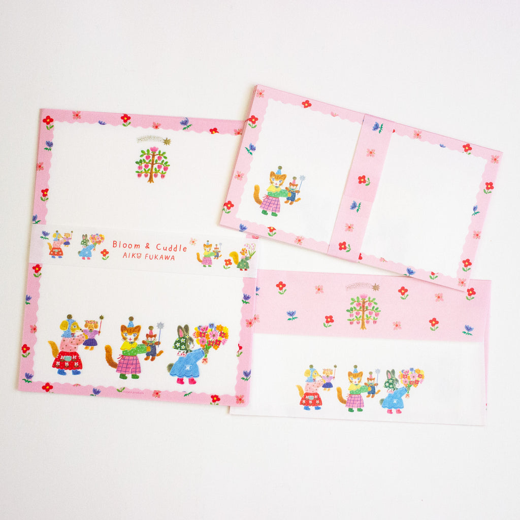 A letterset pink and white stationery sheets and envelopes with colourful cartoon animal illustrations and floral borders, arranged on a plain white background.