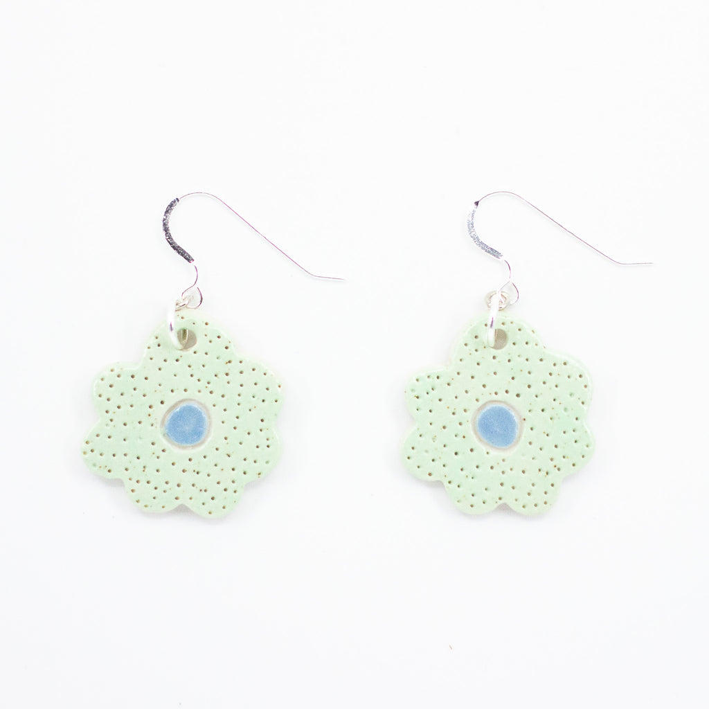 A photo of two bloom earrings with light mint colouring, and a blue centre. Polka dot effect and sterling silver hooks. 