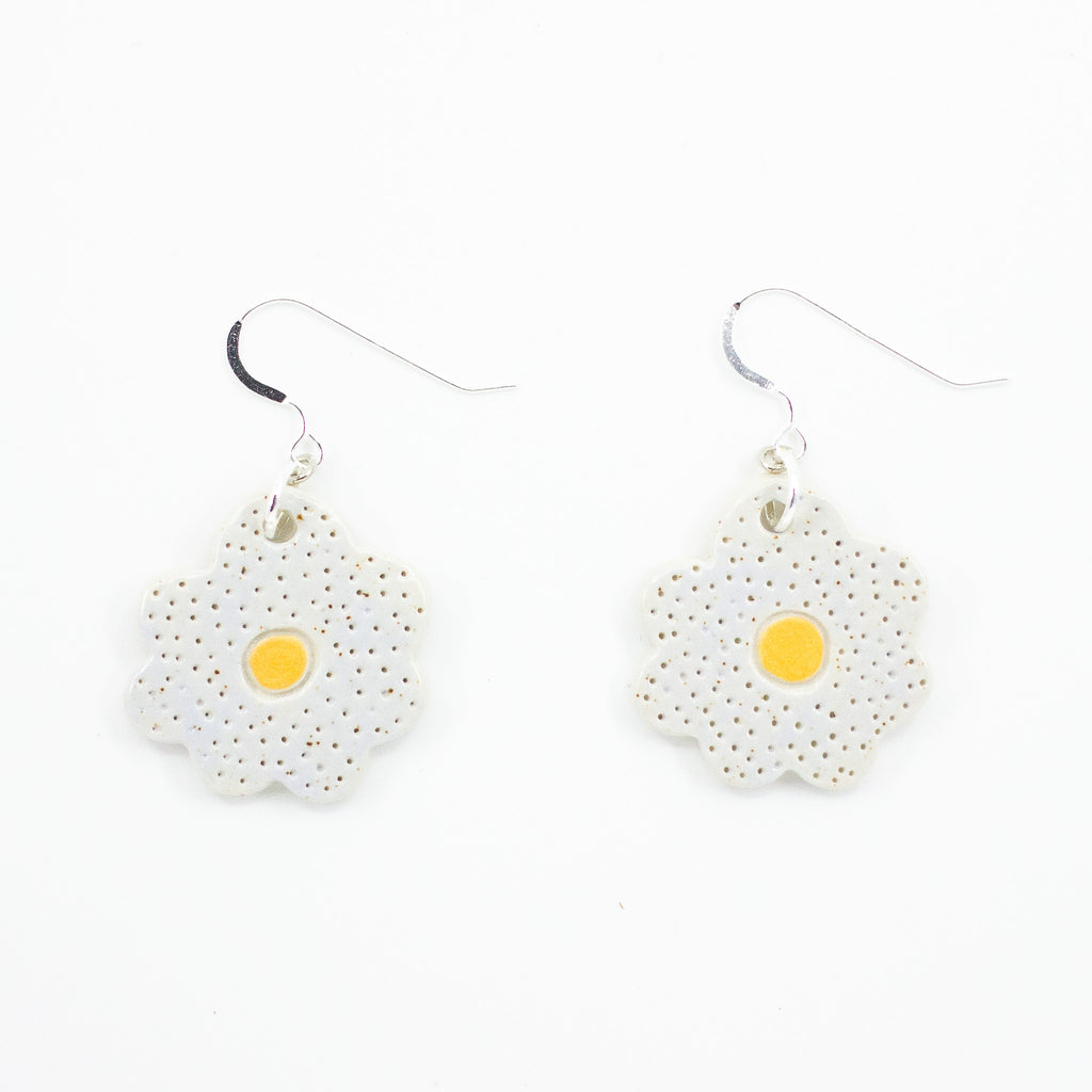 A photo of two bloom earrings with soft lilac colouring, and yellow centre. Polka dot effect and sterling silver hooks. 