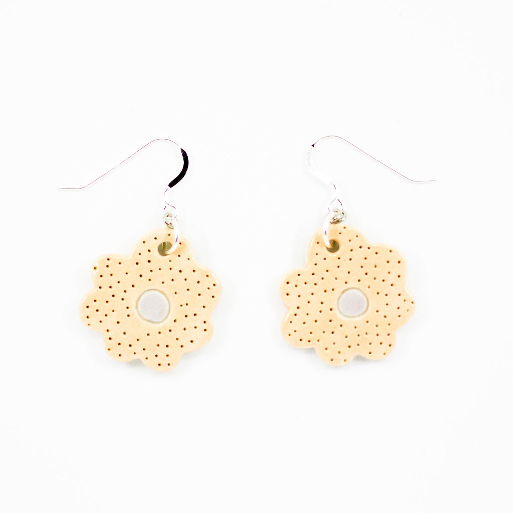 A photo of two bloom earrings with peach colouring, and light lilac centre. Polka dot effect and sterling silver hooks. 