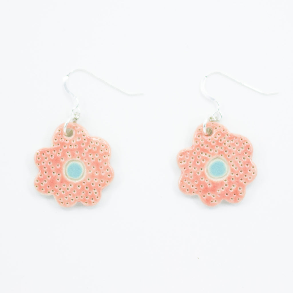A photo of two bloom earrings with rosy pink colouring, and light blue centre. Polka dot effect and sterling silver hooks. 