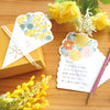 Two decorative Japanese-style note cards with floral illustrations are arranged on a wooden surface with yellow roses, a gold gift box, and a red-and-white striped pen. One card is shown folded over the box with the words 'For you,' and the other is open with handwritten text.