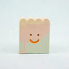 Small rectangular ceramic figure with scallop top and a smiley face design on a light gray background