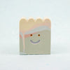 Small rectangular ceramic figure with scallop top and a smiley face design on a light gray background