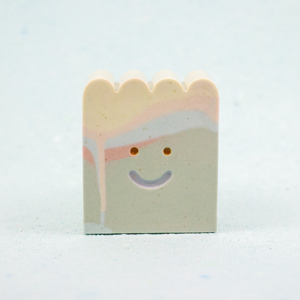 Small rectangular ceramic figure with scallop top and a smiley face design on a light gray background