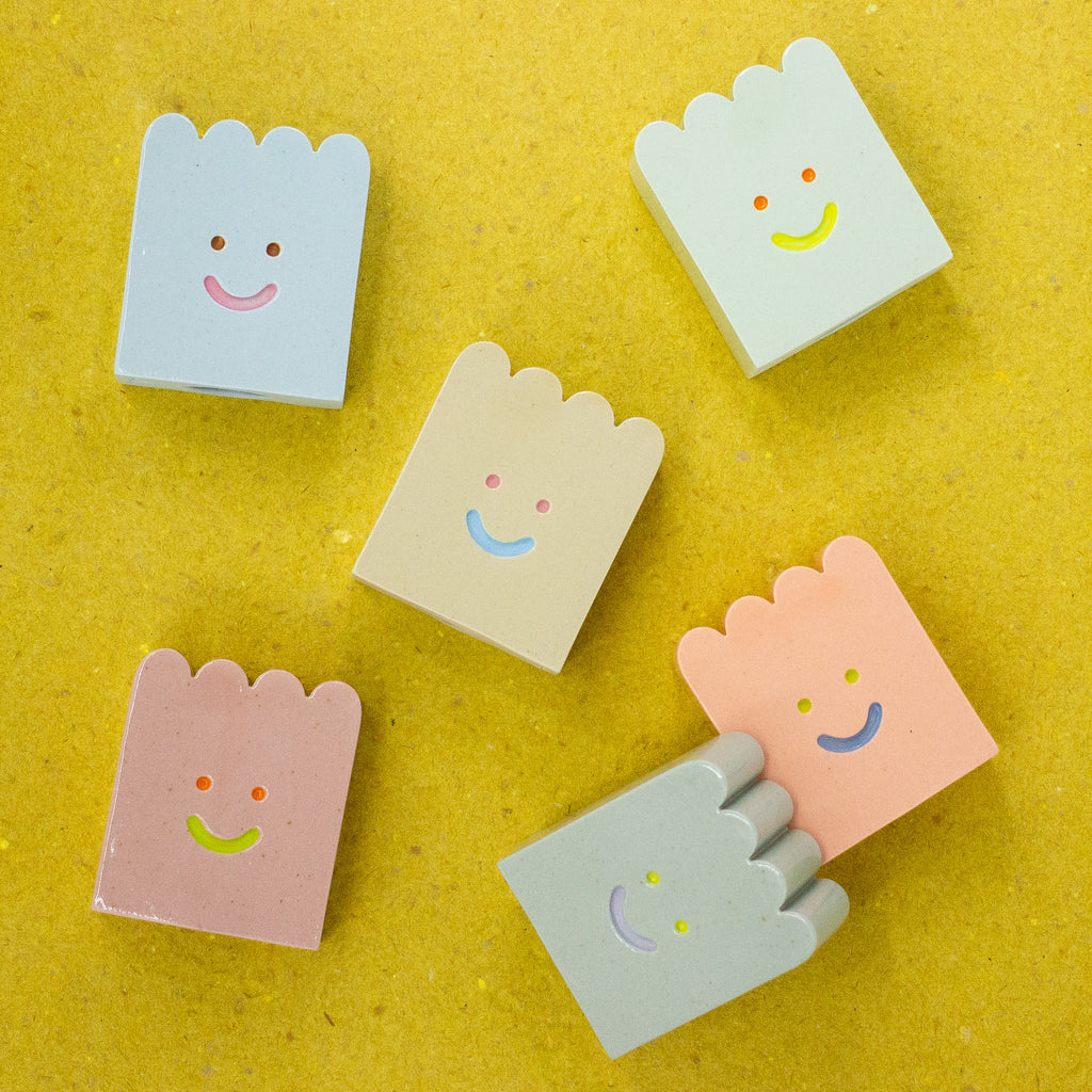 Set of colorful ceramic figures with smiley face designs on a yellow background
