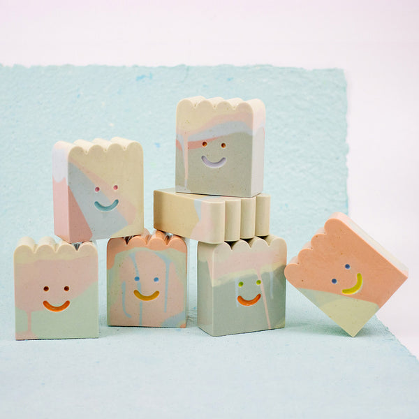Stack of colorful ceramic figures with smiling faces on a light blue background