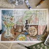 Artistic depiction of two cats at a table with food and flowers, surrounded by art supplies.
