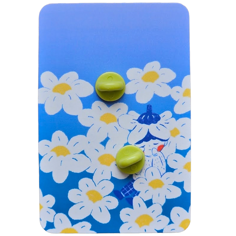 The back of an enamel pin packaging with two green rubber stopper, mounted on a blue floral patterned backing card.