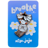 A cute enamel pin of a girl with a flower crown sitting among daisies, mounted on a blue backing card that reads 'breathe' and 'Misu Juju'.