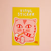 A vinyl sticker featuring a pink cartoon cat holding a straw stick and blowing a bubble on a bright yellow backing card, displayed against a soft pink background.