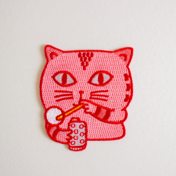 Embroidered patch of a cat blowing bubble on a white background