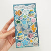 Hand holding a glitter sticker sheet featuring sea-themed illustrations with title 'Bubble Bubble'. 