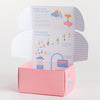 An open pink cardboard box with illustrated instructions on the inside flaps, titled 'Using Your Bubble Buddy' and 'How Bubble Buddy Is Made,' photographed on a clean white background.