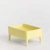 Yellow plastic soap dish with drainage holes on a light grey background