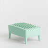 A mint green plastic footrest with a textured, dimpled top surface and four short legs, shown on a light background.