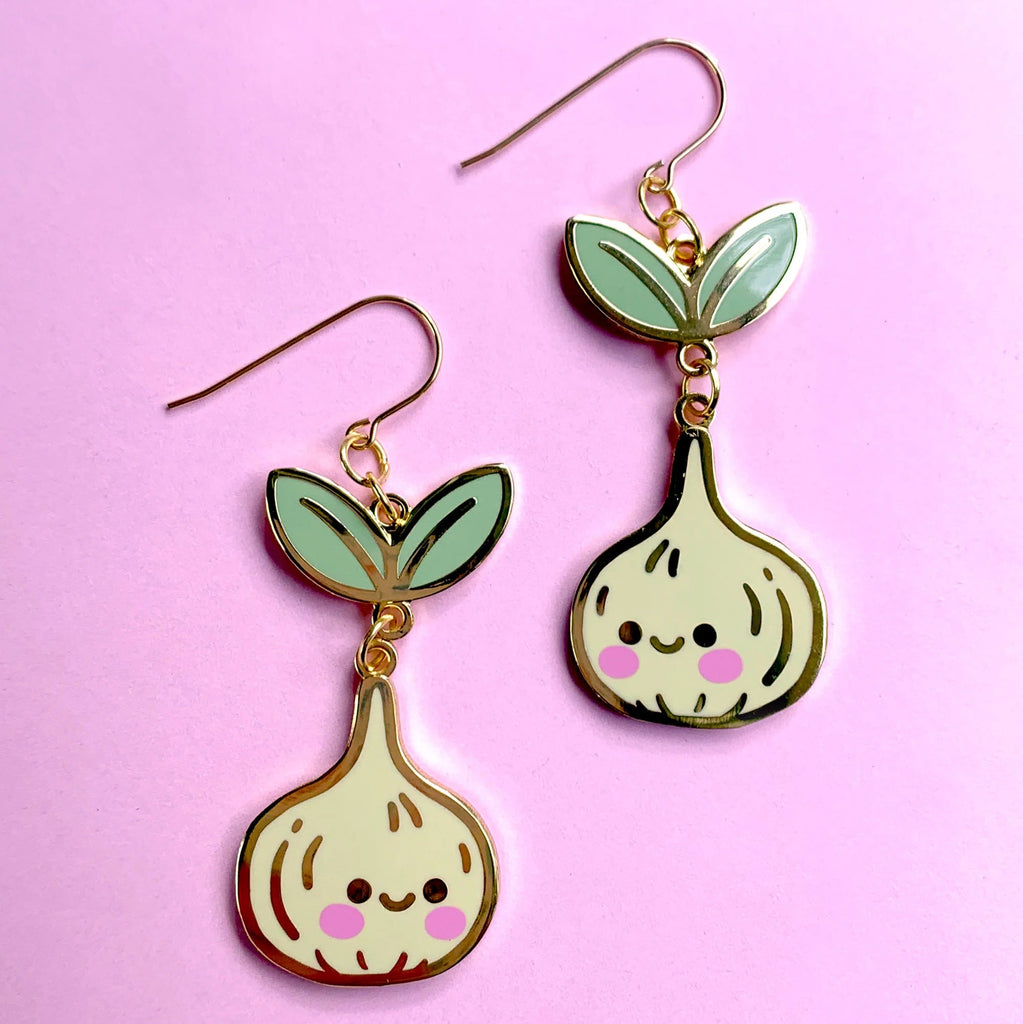 Pair of garlic-shaped earrings with smiling faces on a pink background